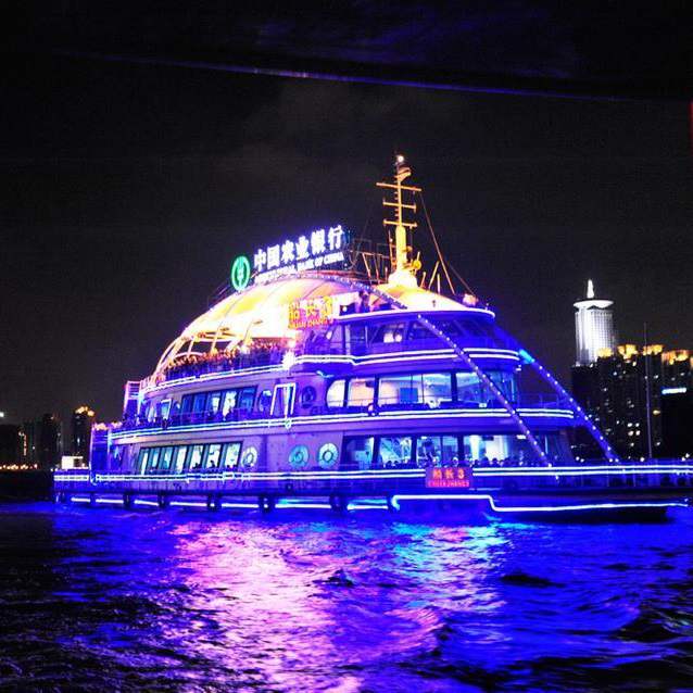 Sightseeing boat outlined with blue and purple lighting at night
